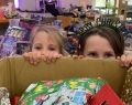 Two girls peek over box of donated gifts